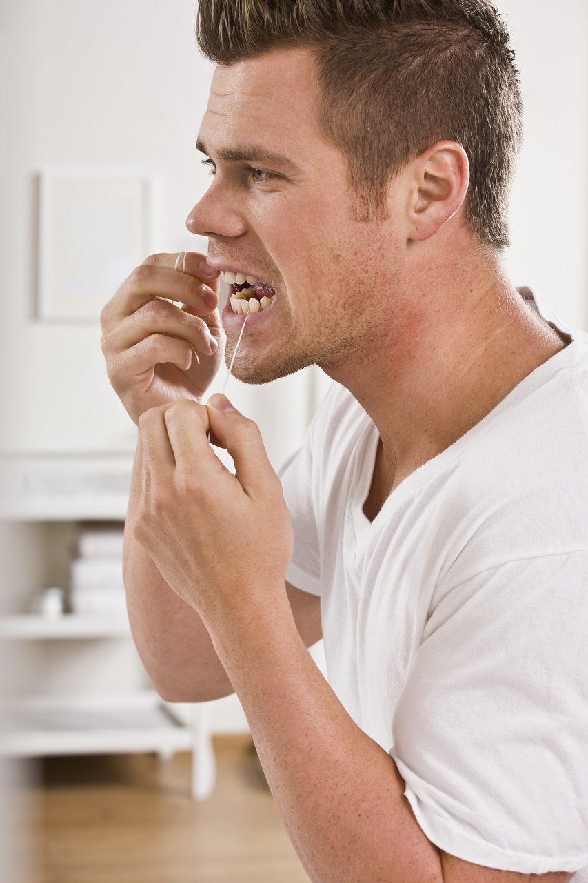 man flossing his teeth to stop gum disease