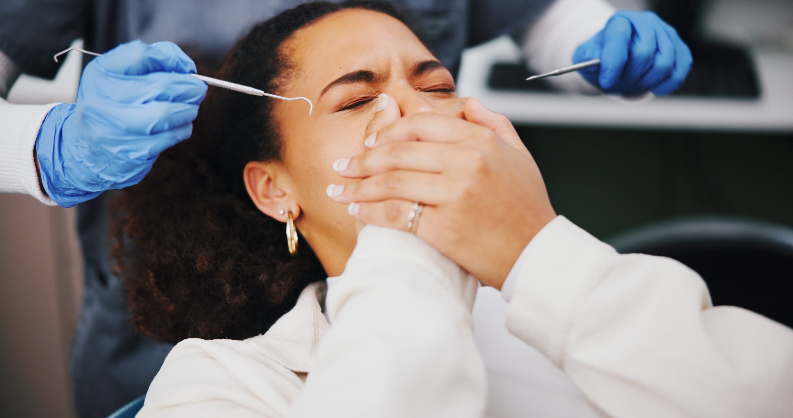 scared female dental patient covering her mouth